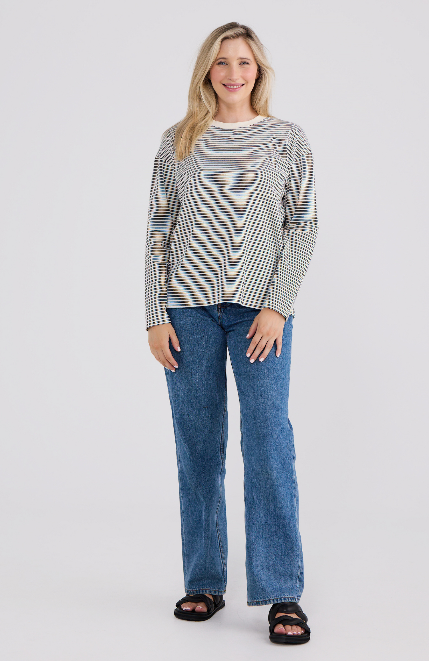 Woman wearing a striped sweater and blue jeans on a white background