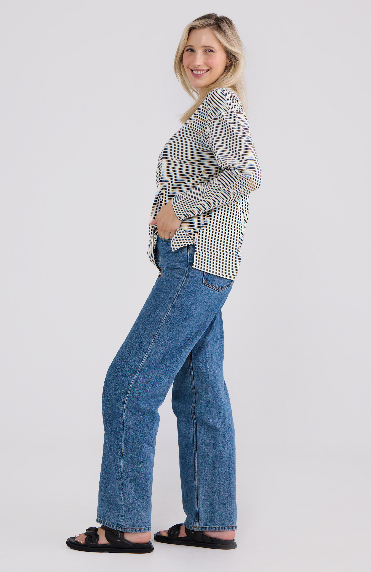 Woman wearing a striped sweater and blue jeans on a white background