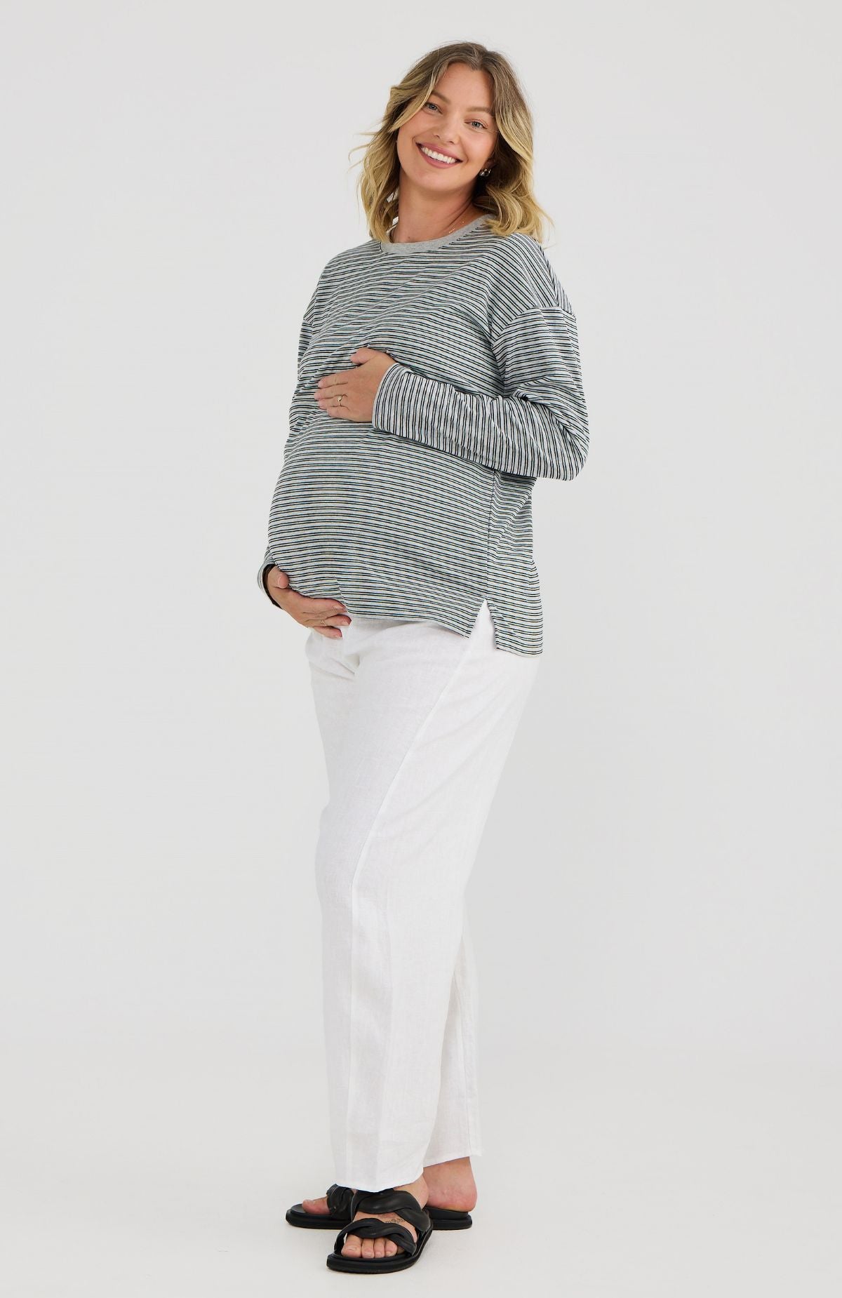 Woman wearing a striped long-sleeve top and white pants on a white background