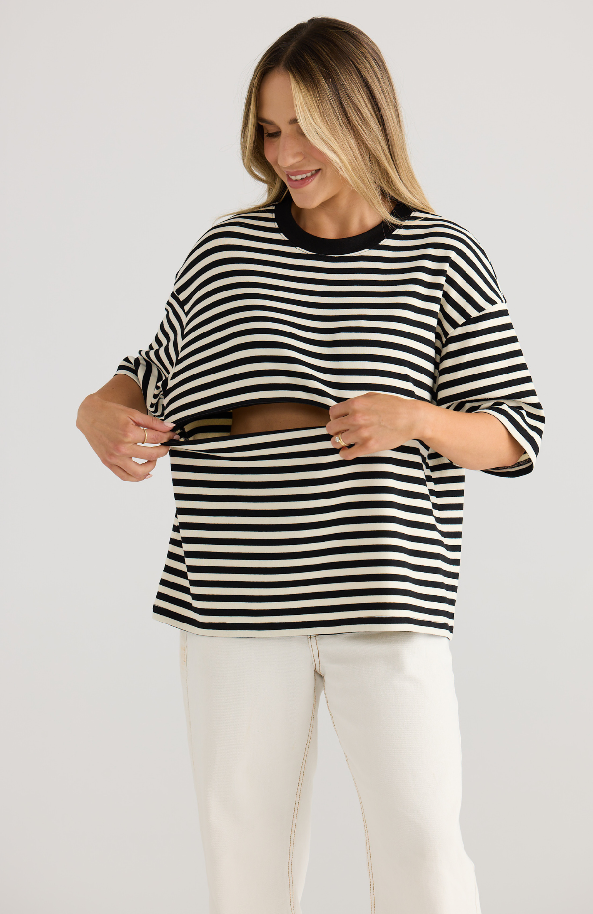 Woman wearing a breastfeeding-friendly black and white striped top with a plain background