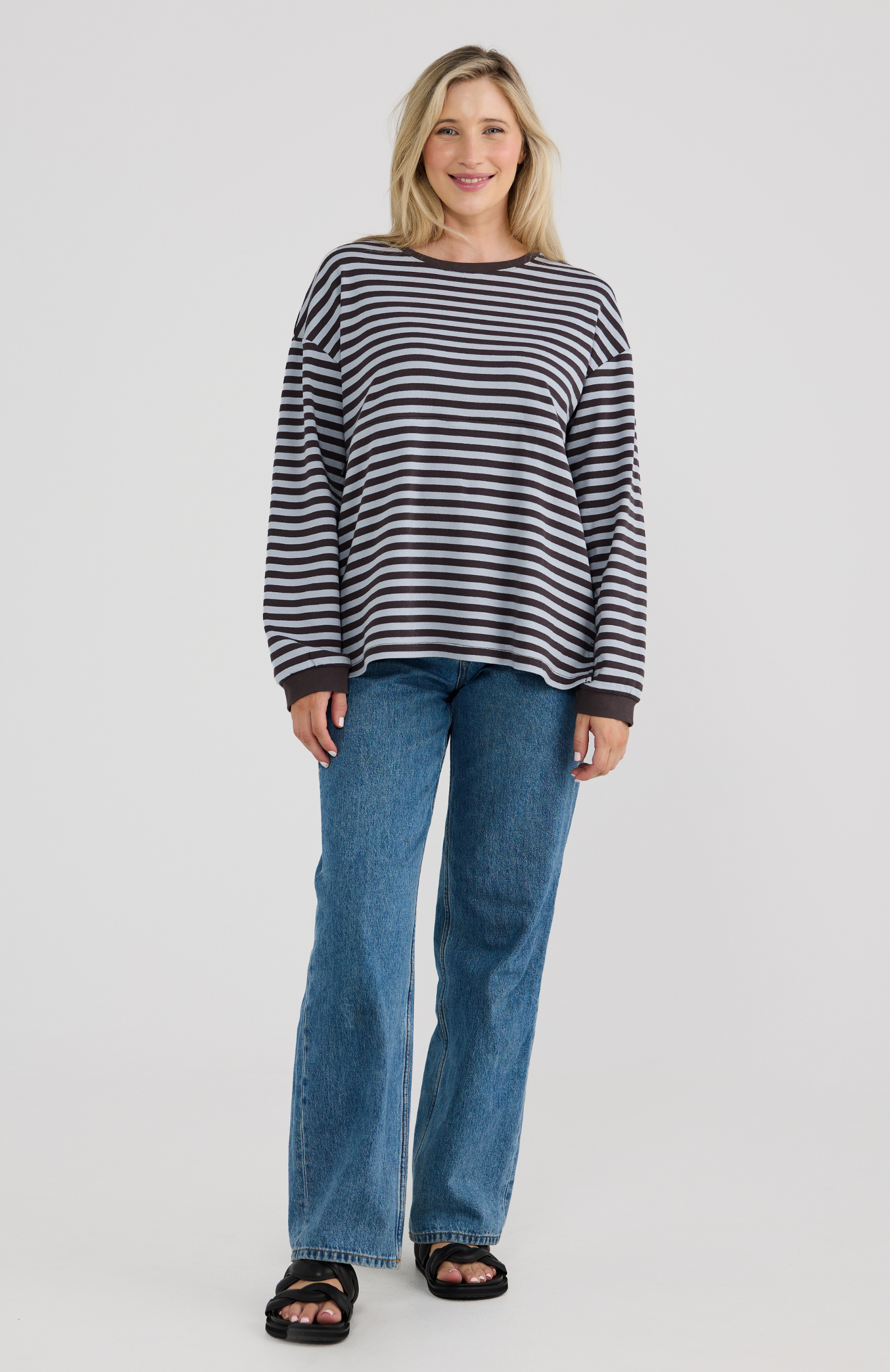 Woman wearing a striped sweater and blue jeans on a white background