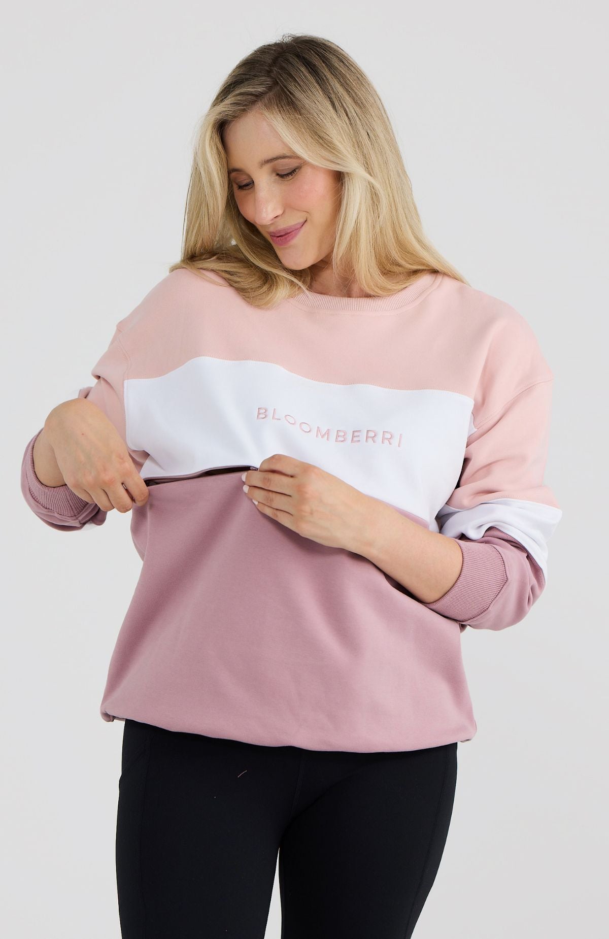 Woman wearing a pink and white sweatshirt with 'Bloomberry' branding on a light gray background