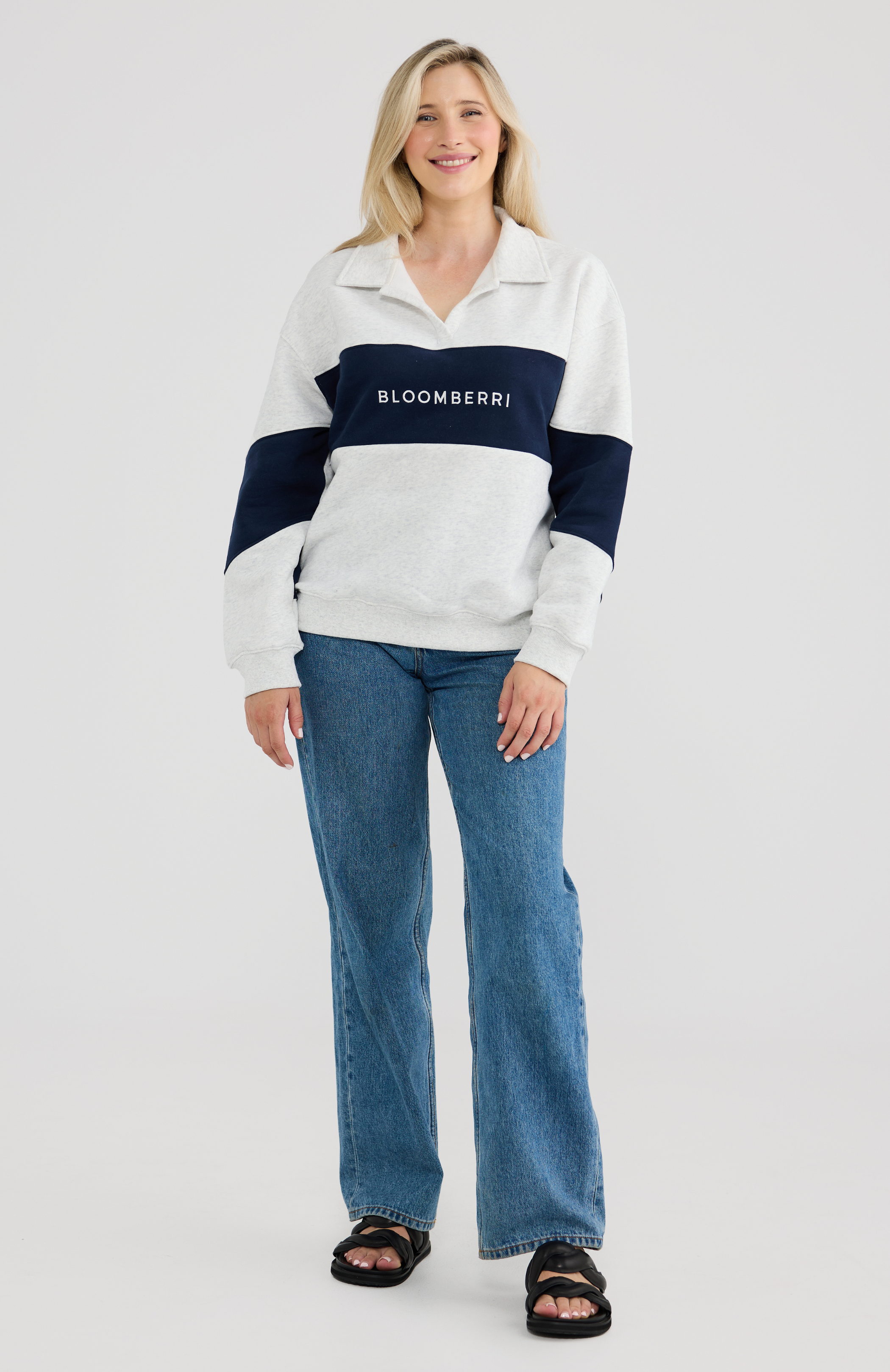 Woman wearing a grey and navy striped nursing sweater with 'Bloomberri' logo, standing against a plain background.