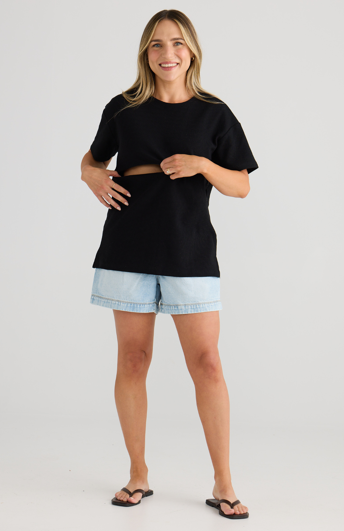 Woman wearing a black top and light blue shorts on a white background