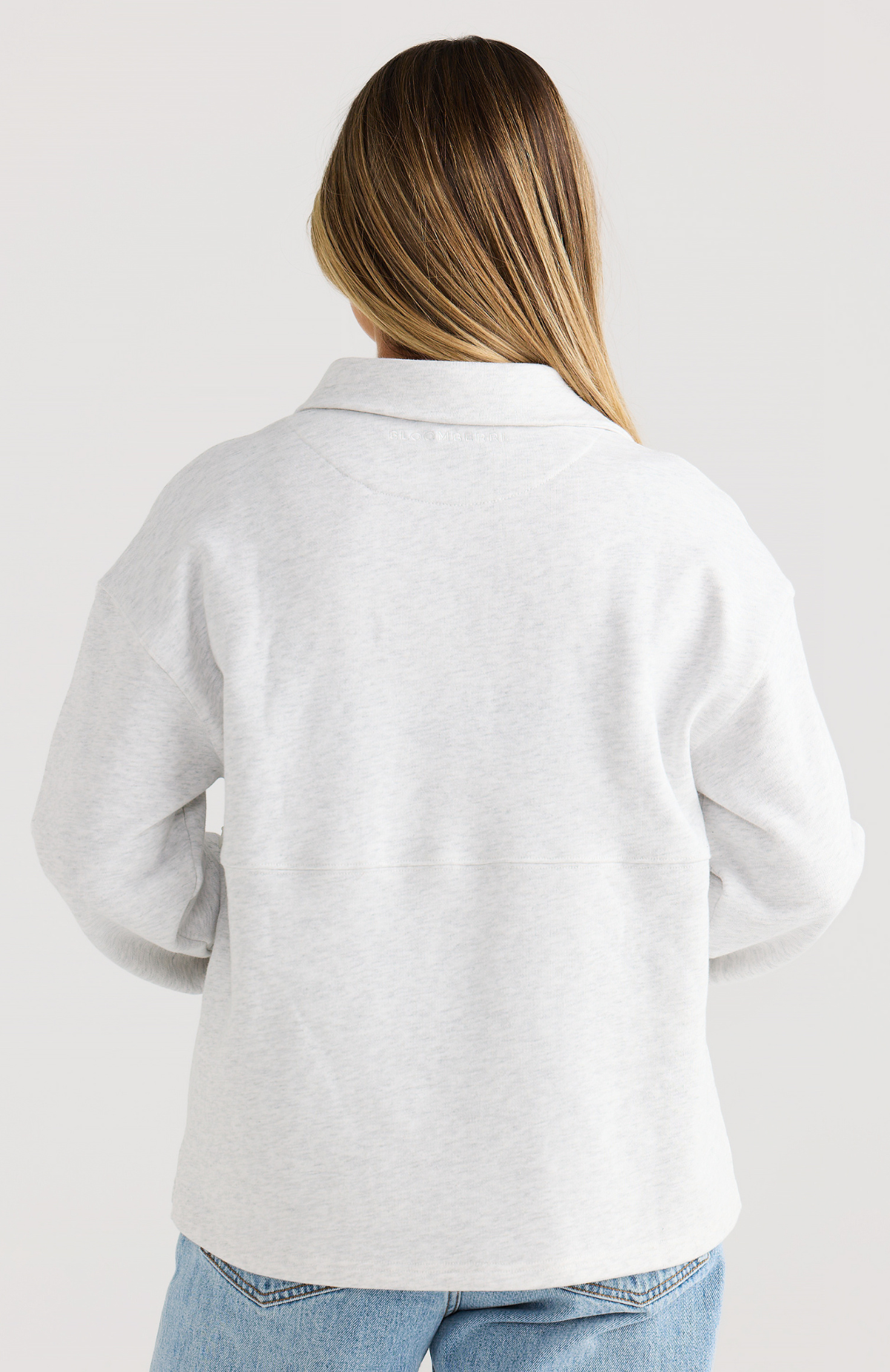 Person wearing a light gray cardigan on a plain background