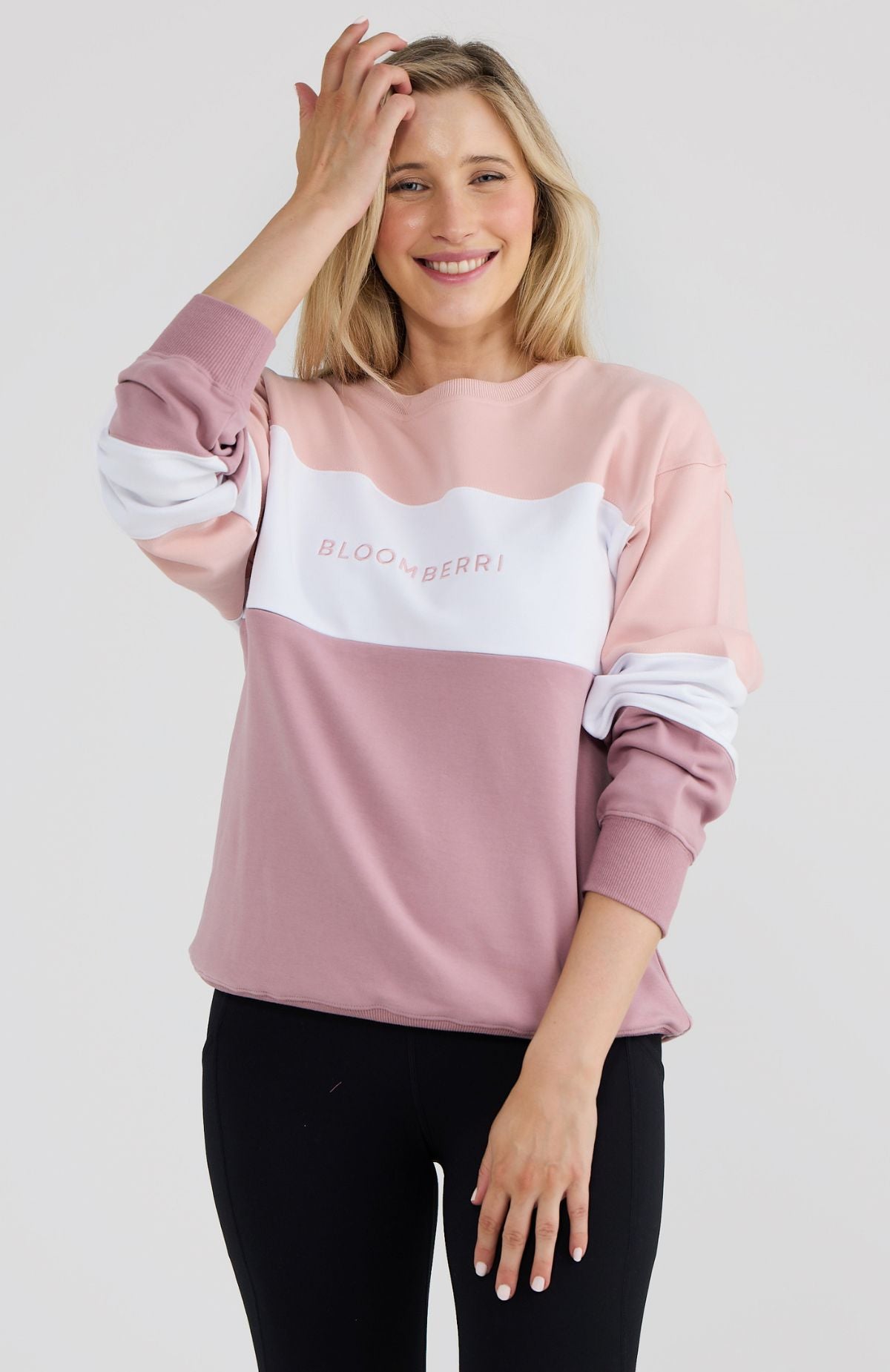 Woman wearing a pink and white sweatshirt with text on a plain background