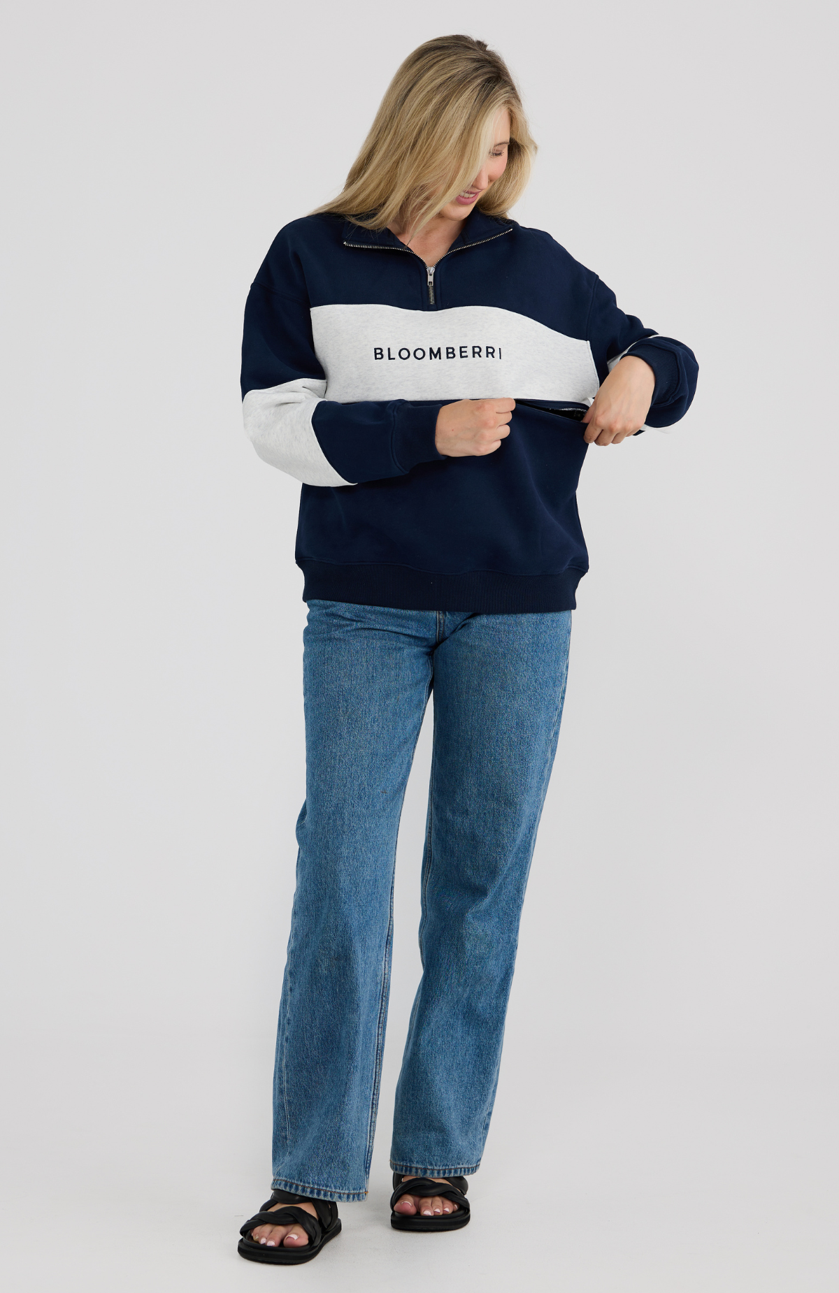 Woman wearing a navy and grey striped sweater with 'Bloomberri' logo, standing against a plain background.