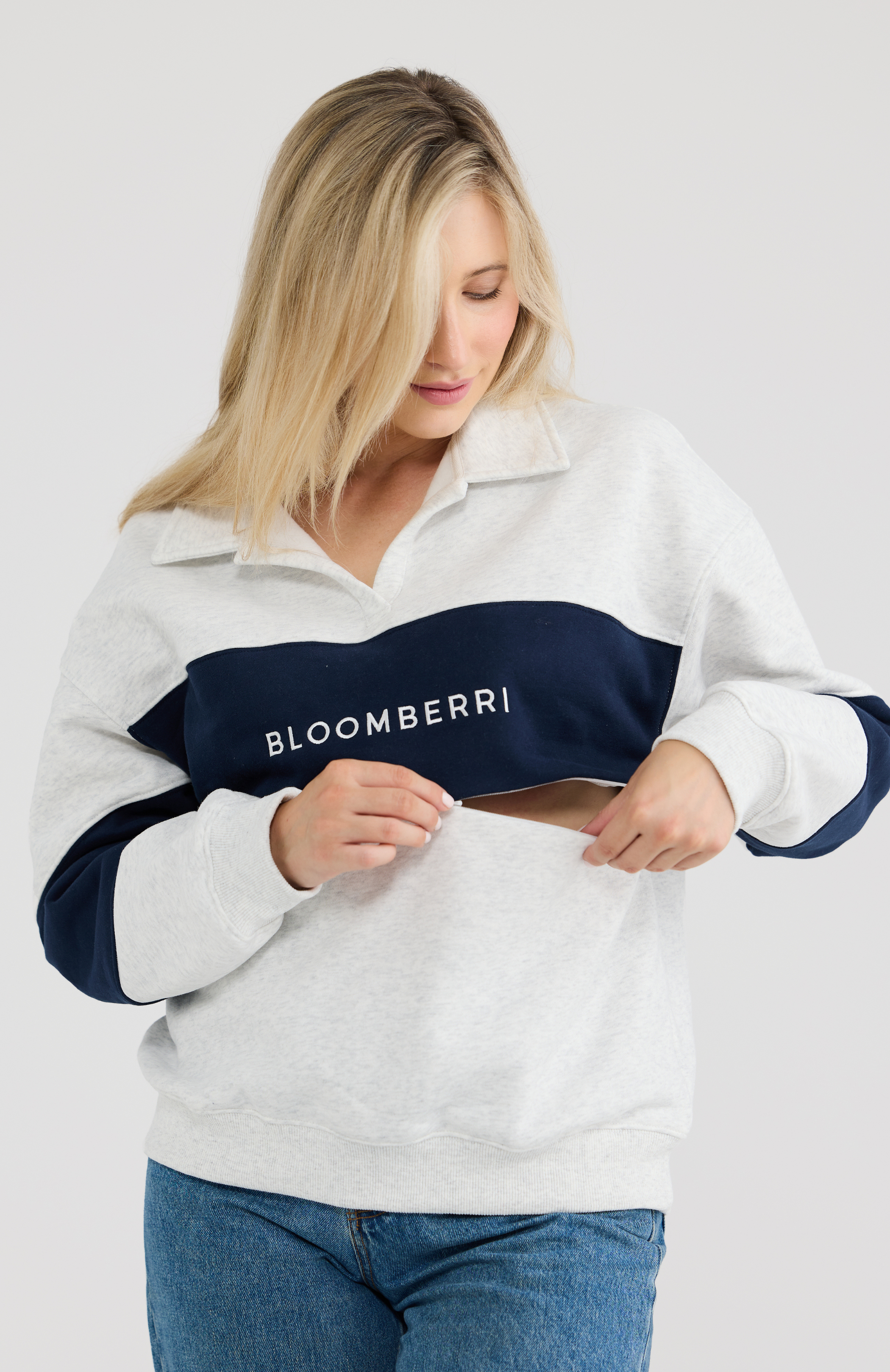 Woman wearing a grey and navy sweatshirt with 'Bloomberg' branding on a plain background