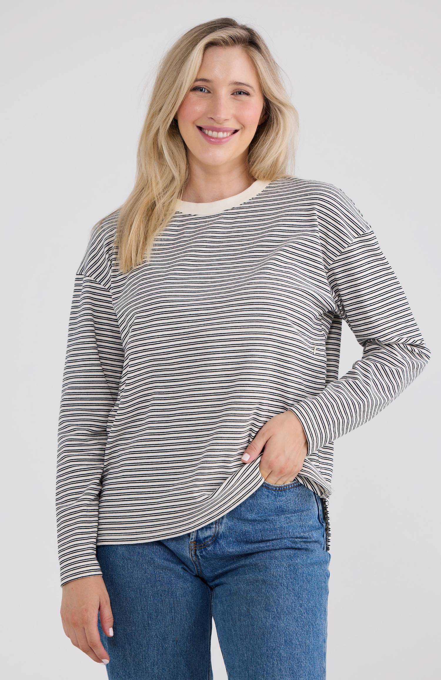 Woman wearing a striped nursing-friendly long-sleeve top and jeans on a white background