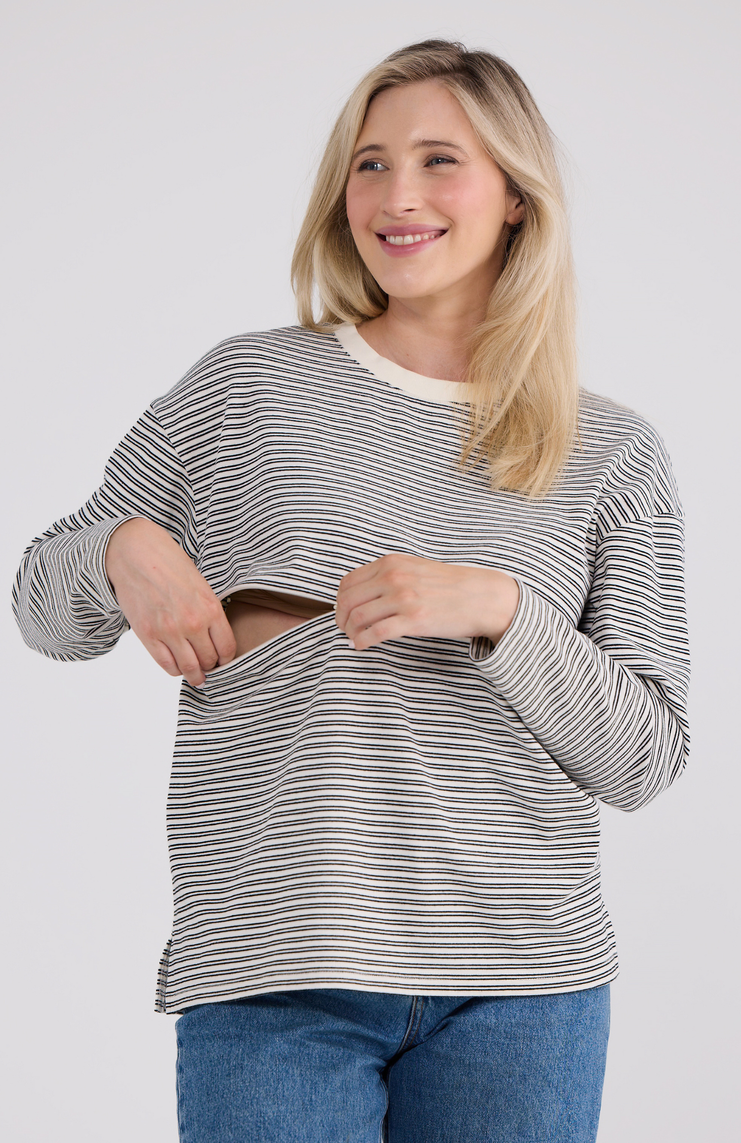 Woman wearing a striped sweater and jeans on a plain background