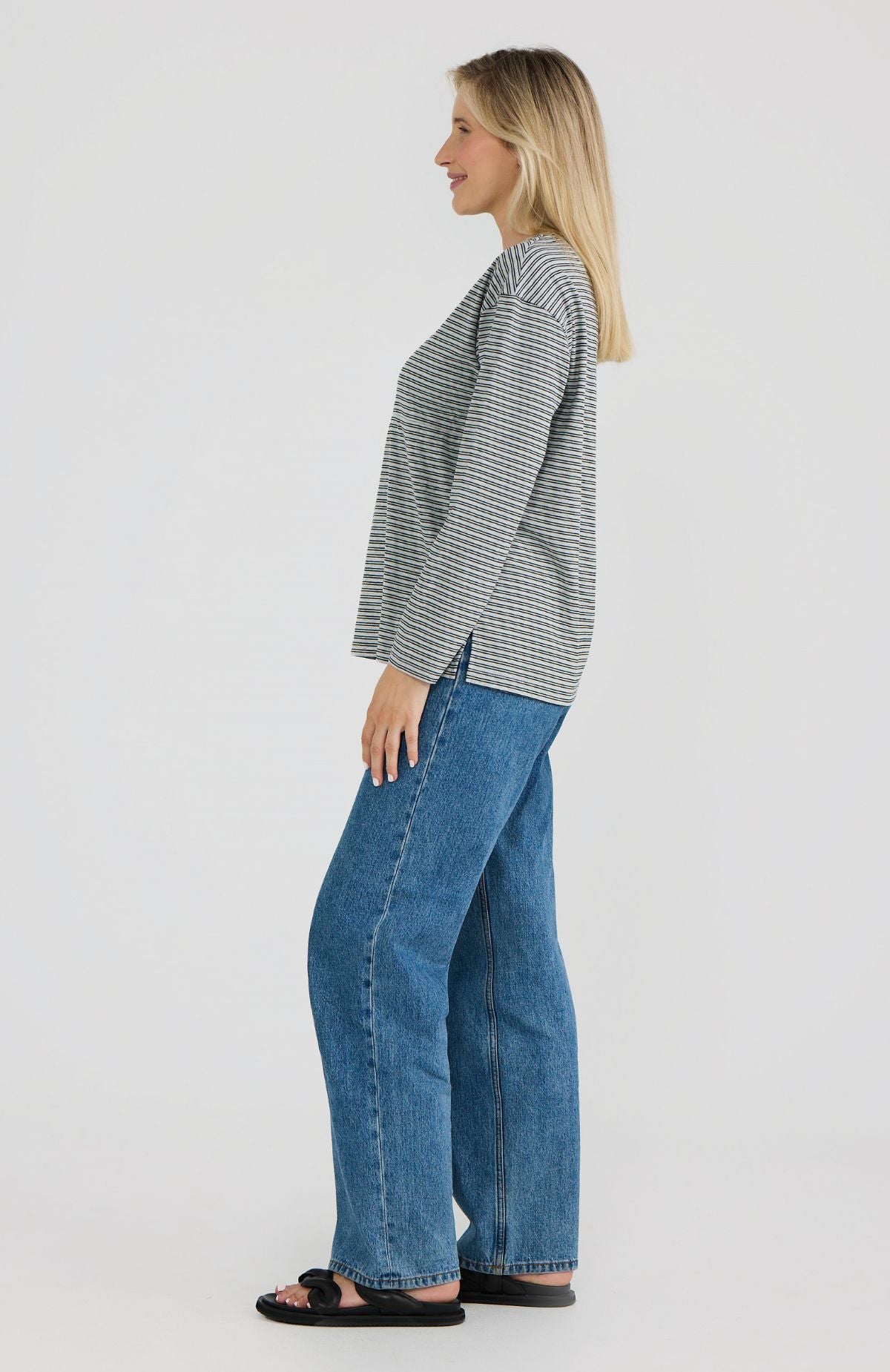 Woman wearing a striped shirt and blue jeans on a white background