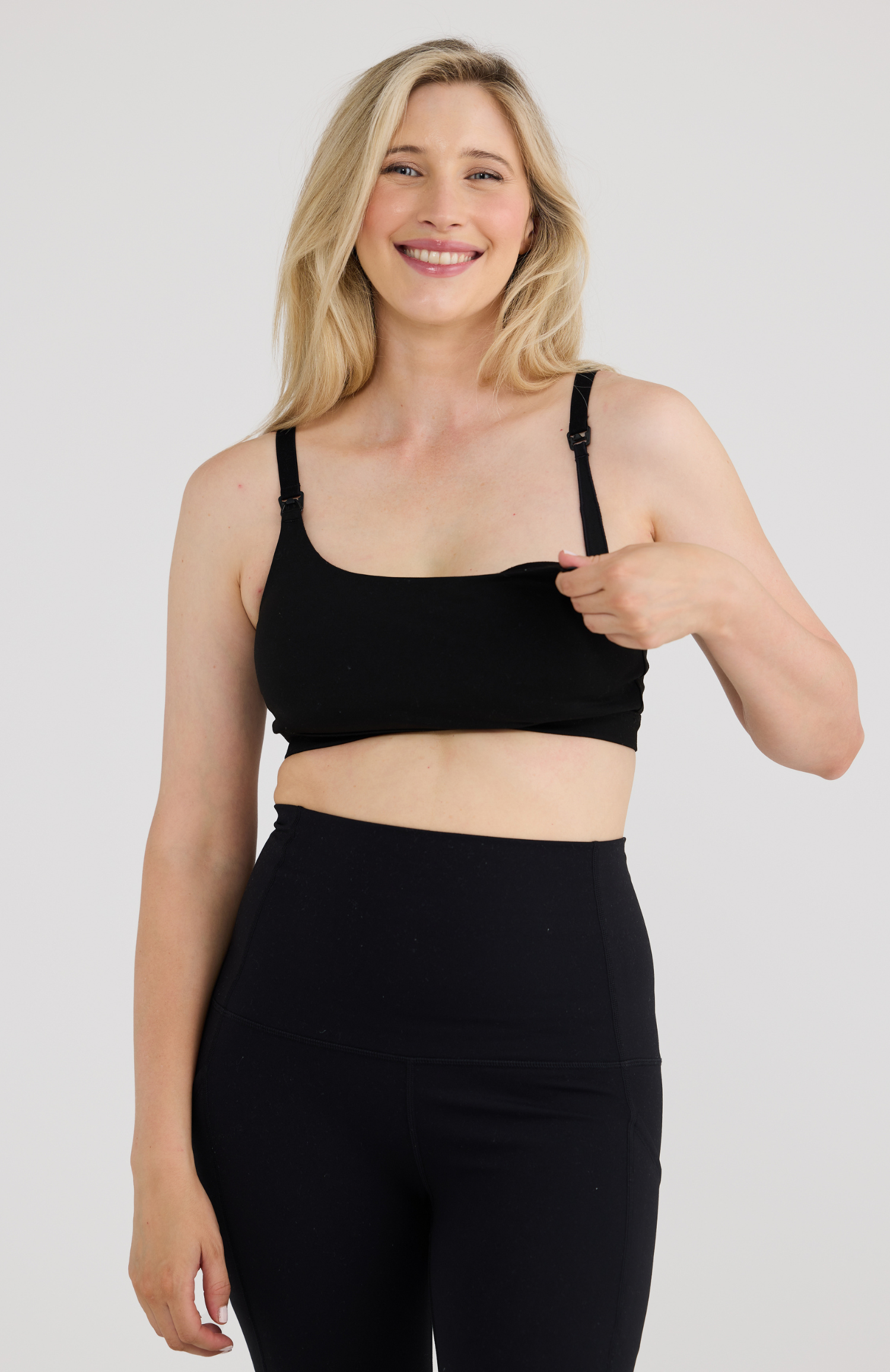 Woman wearing a black sports bra and leggings on a plain background