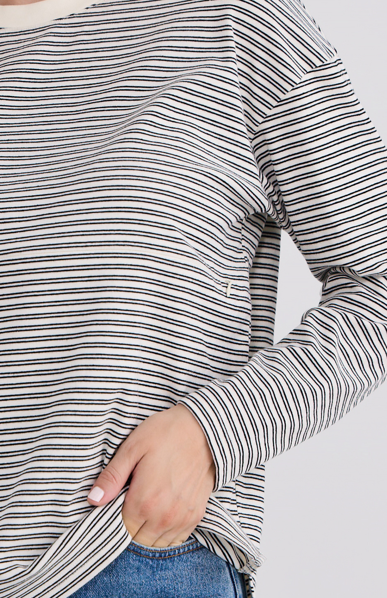 Close-up of a person wearing a black and white striped long-sleeve top with a blurred background.
