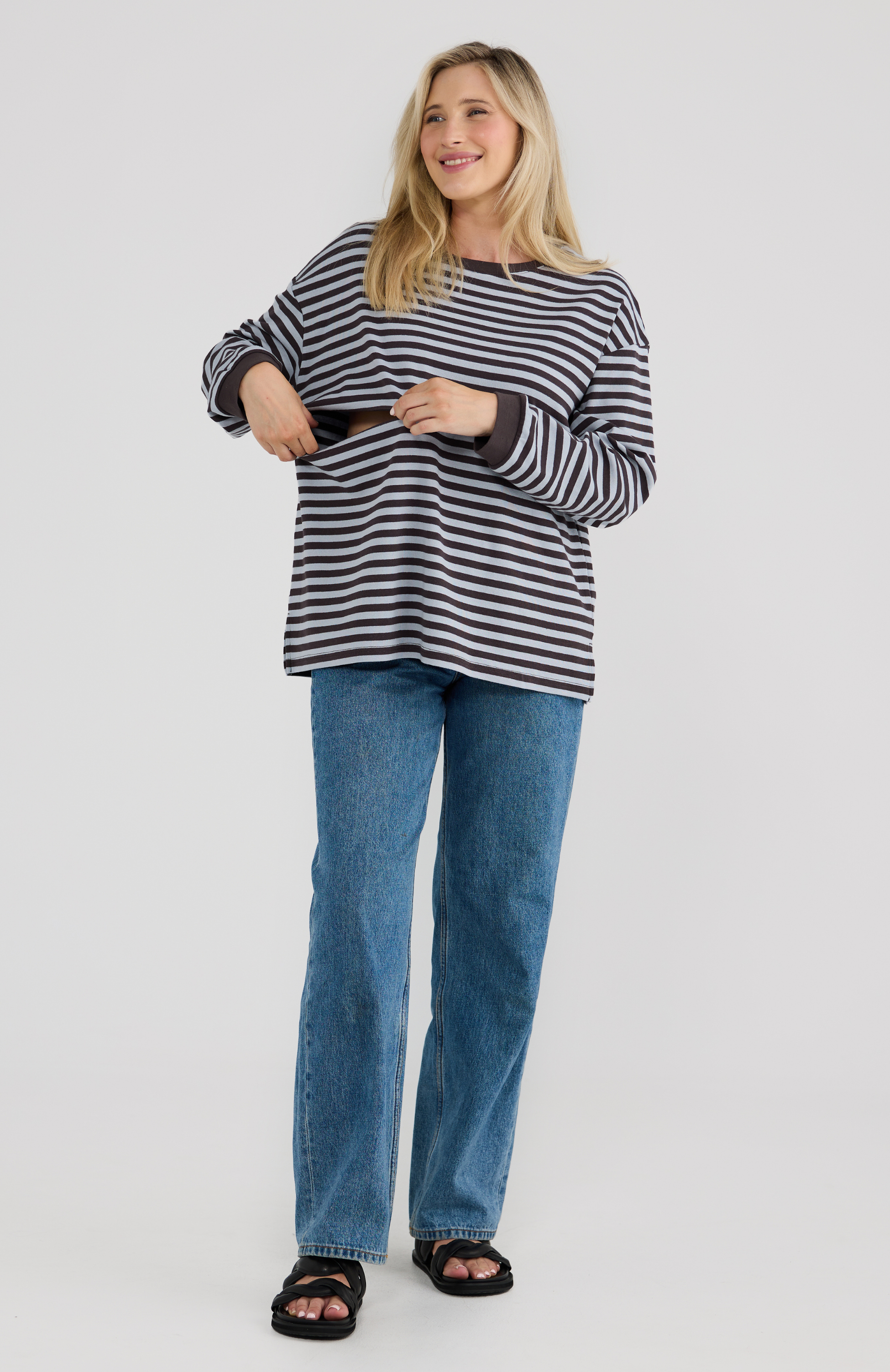 Woman wearing a striped sweater and blue jeans on a white background