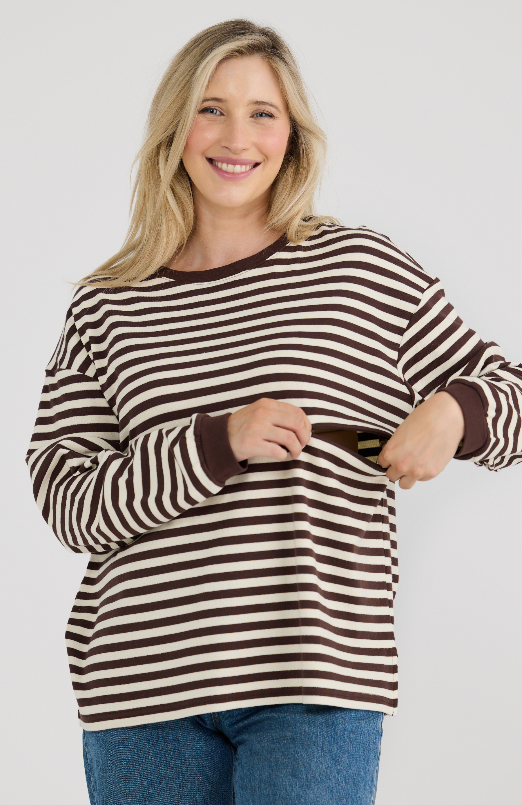 Woman wearing a brown and white striped sweater on a plain background