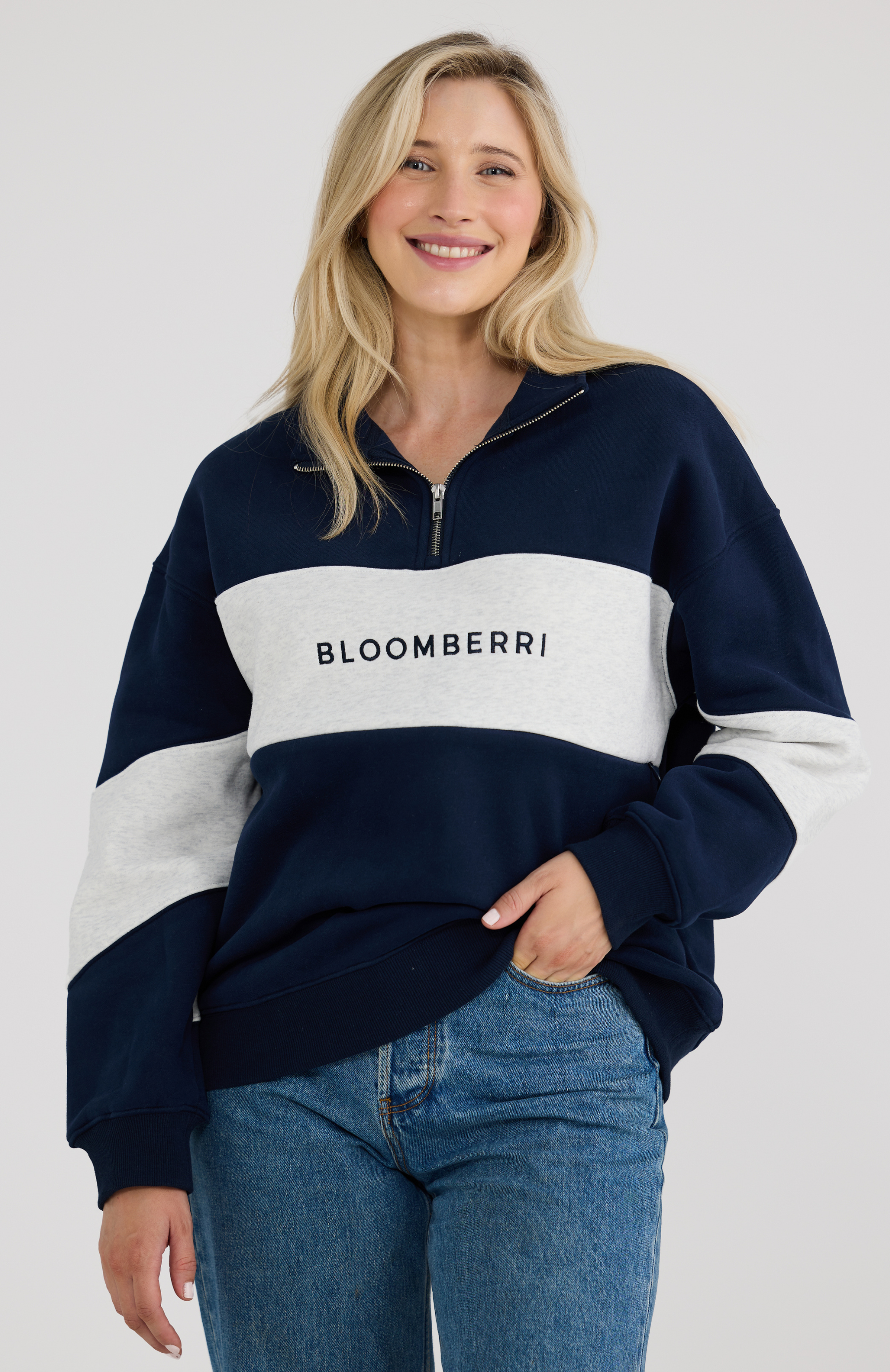 Woman wearing a navy and grey striped sweater with 'BLOOMBERRI' logo, standing against a plain background.