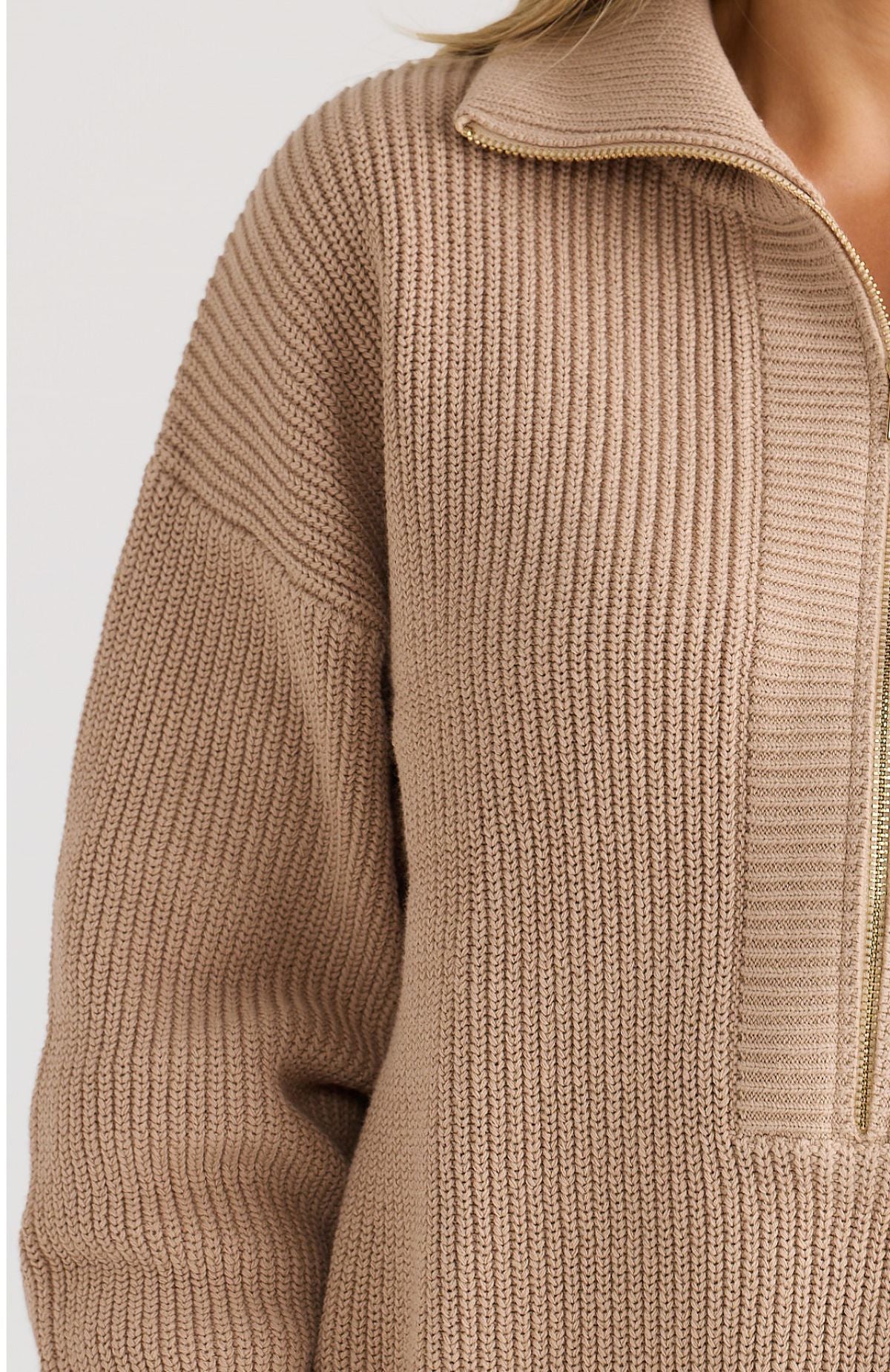 Close-up of a beige knit sweater with a high collar on a white background