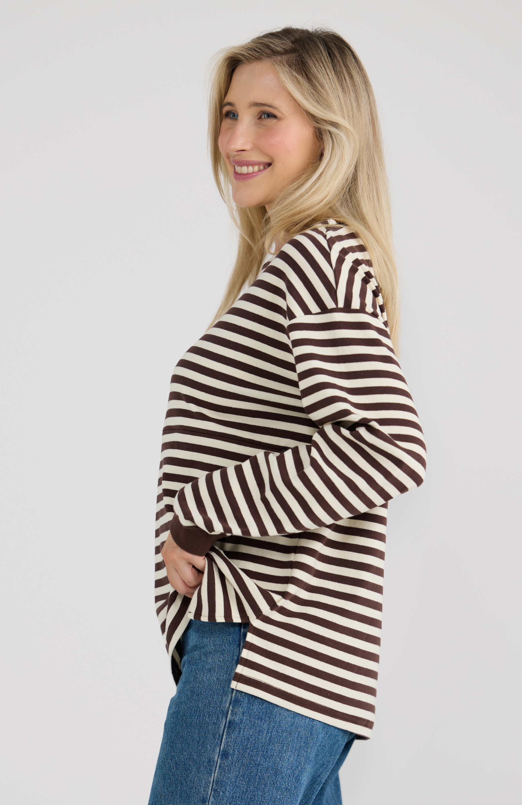 Woman wearing a brown and white striped long sleeve top on a plain background