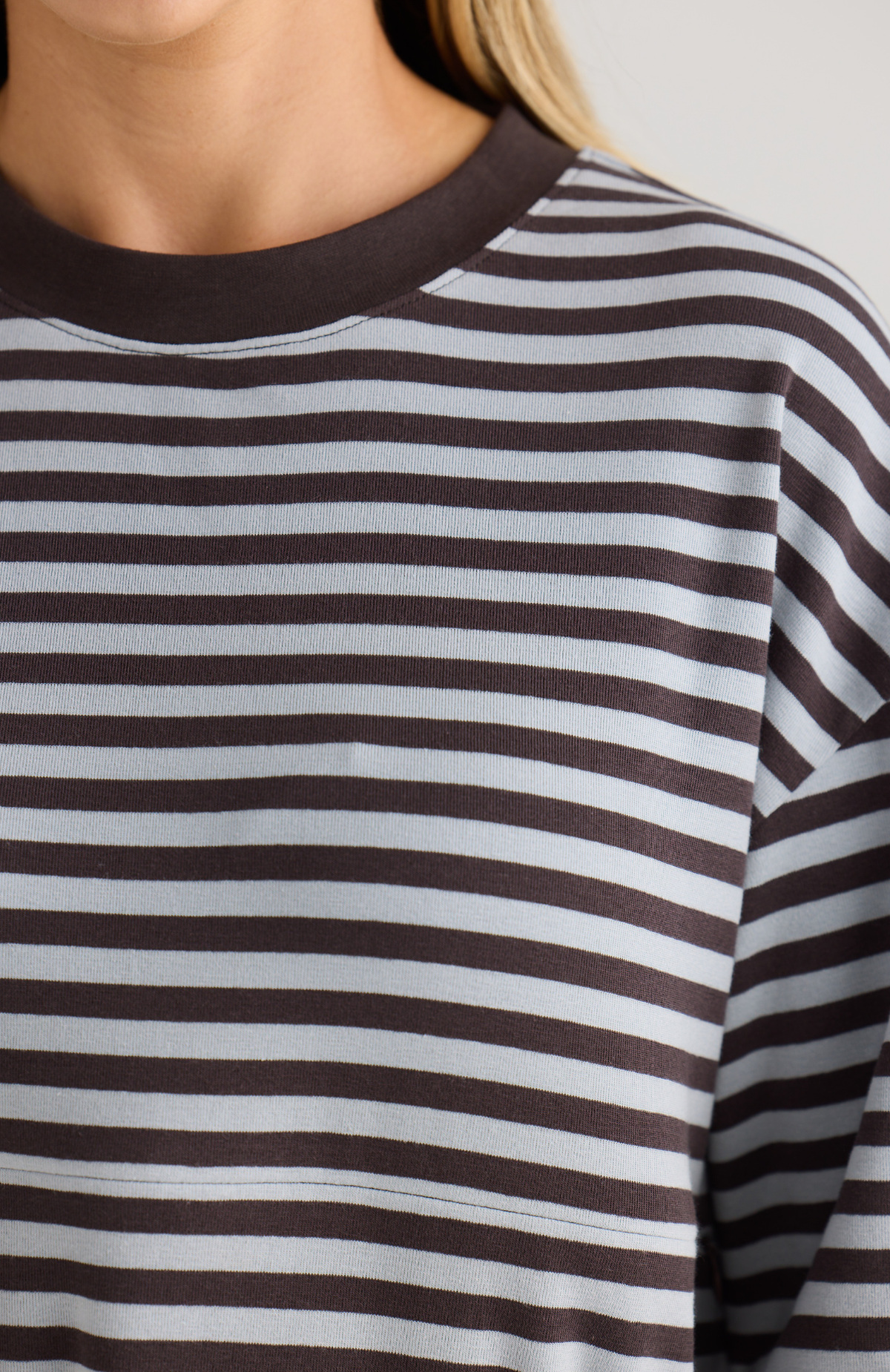 Close-up of a person wearing a blue and chocolate striped top.