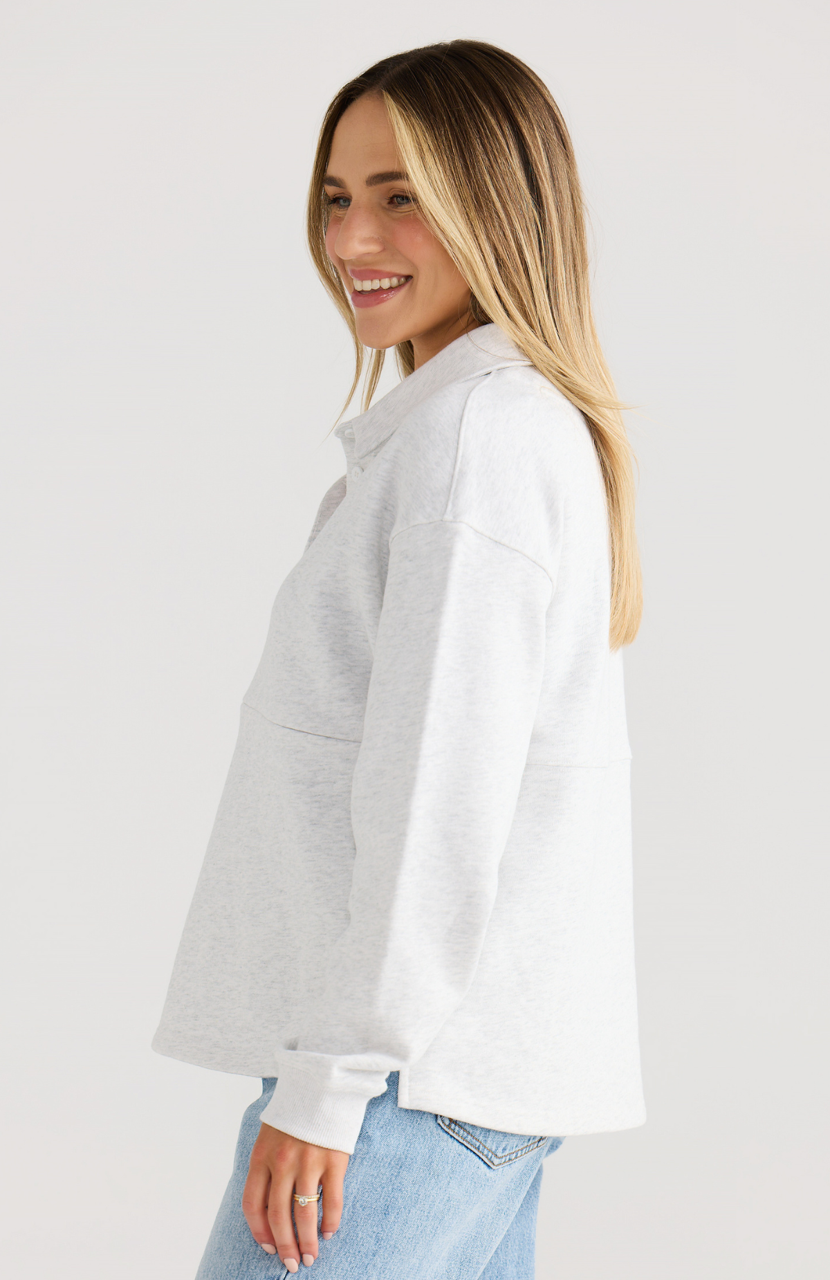 Woman wearing a light grey jumper with a plain background