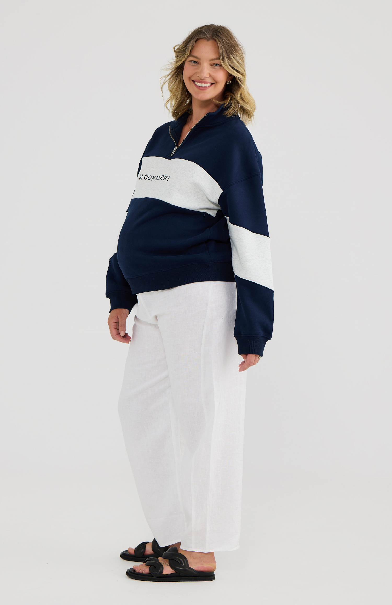 Woman wearing a navy and grey color-blocked sweater on a white background