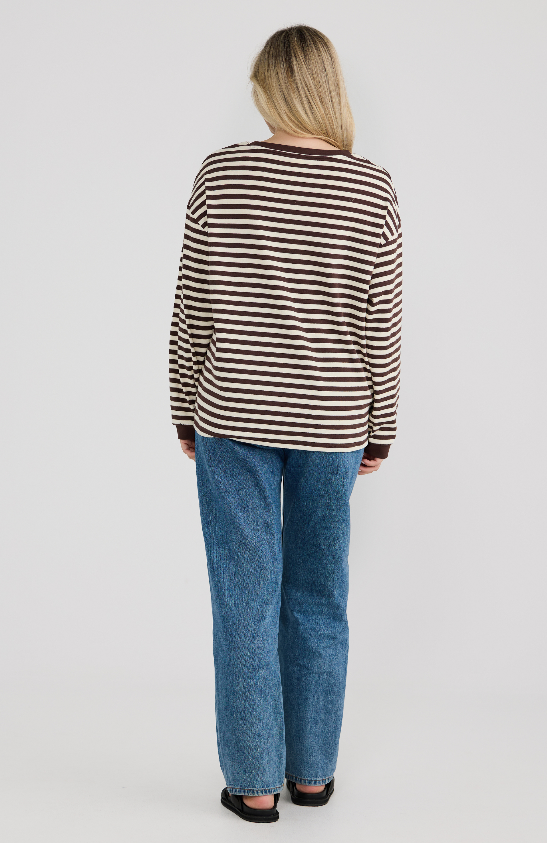 Person wearing a striped shirt and jeans on a plain background