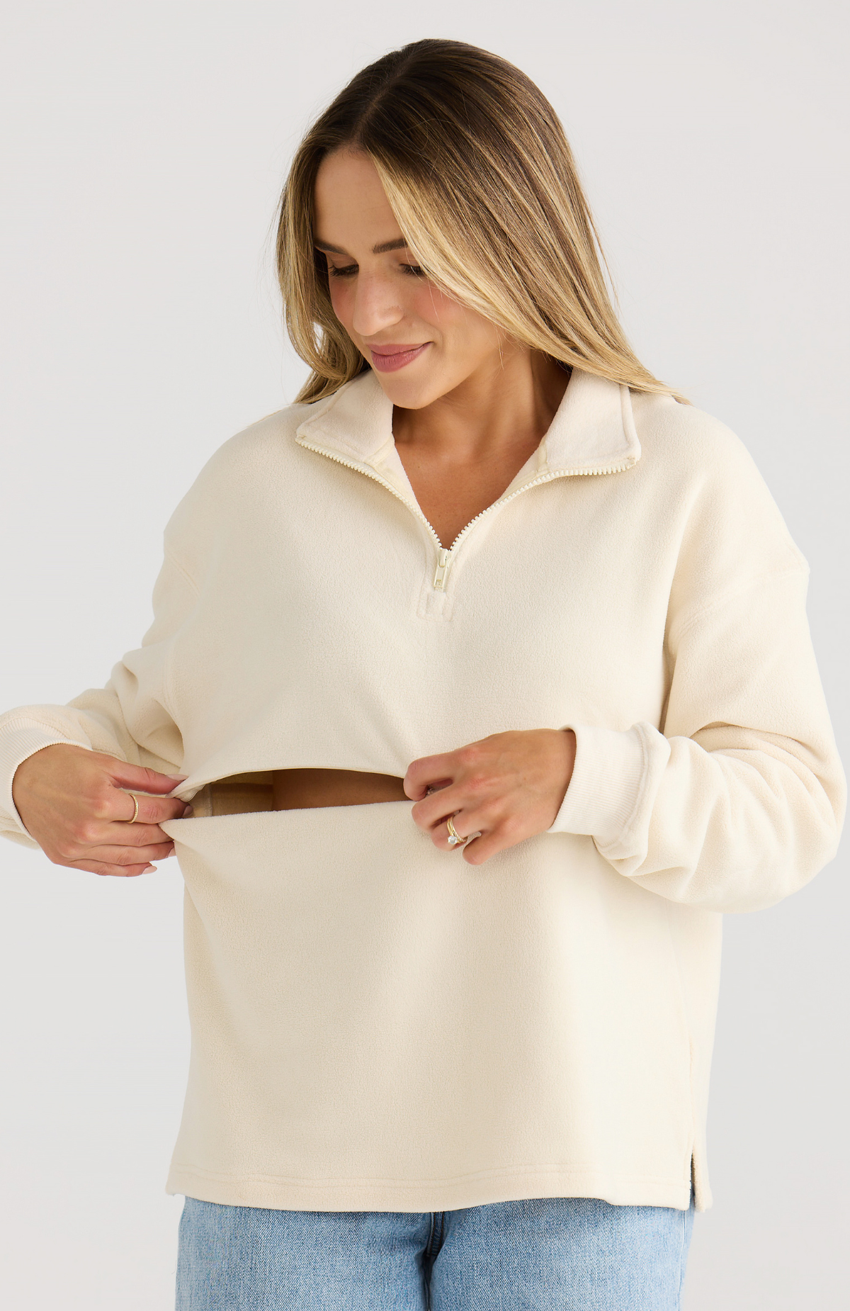 Woman wearing a cream-colored sweater against a white background