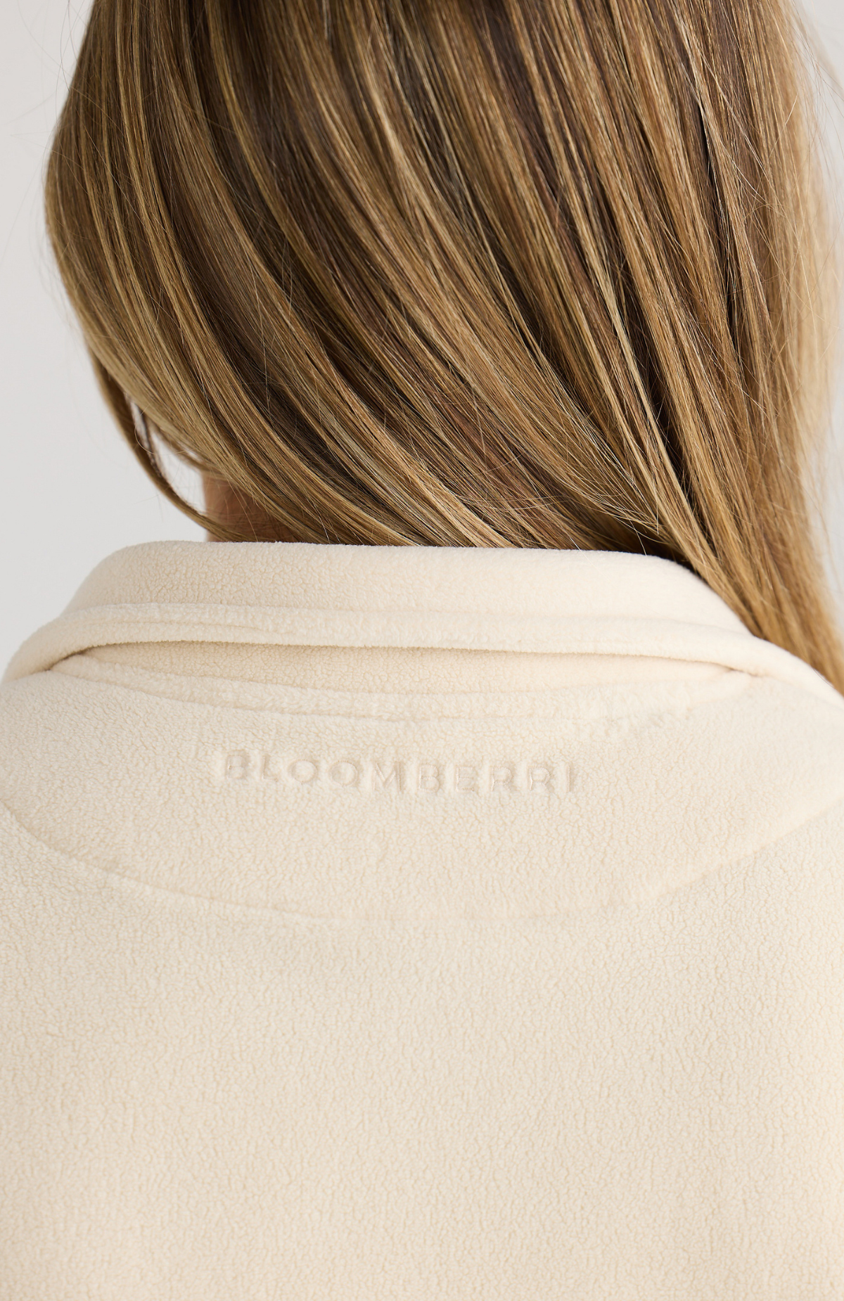 Close-up of a person wearing a cream jumper with Bloomberri branding