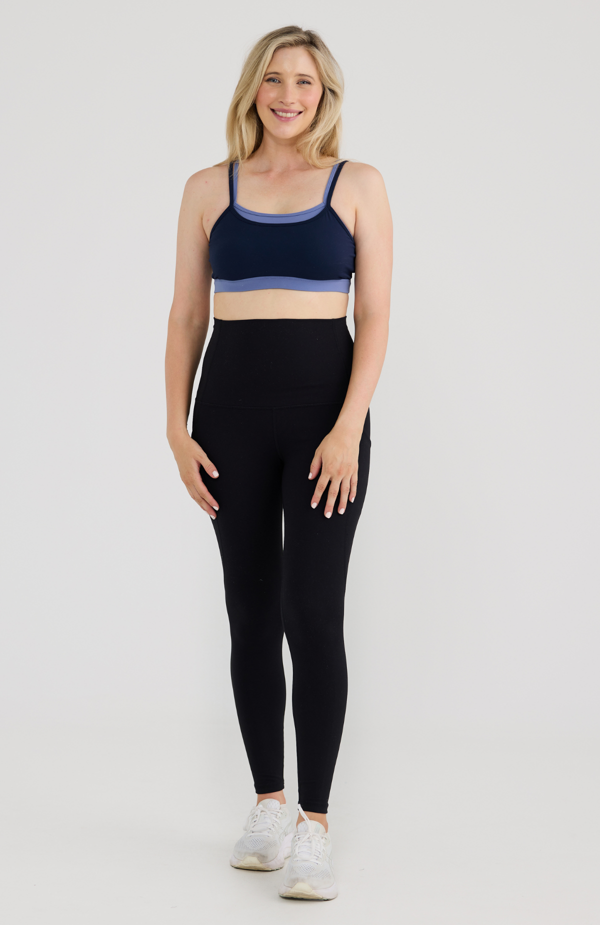 Woman wears navy bra and black tights on grey background