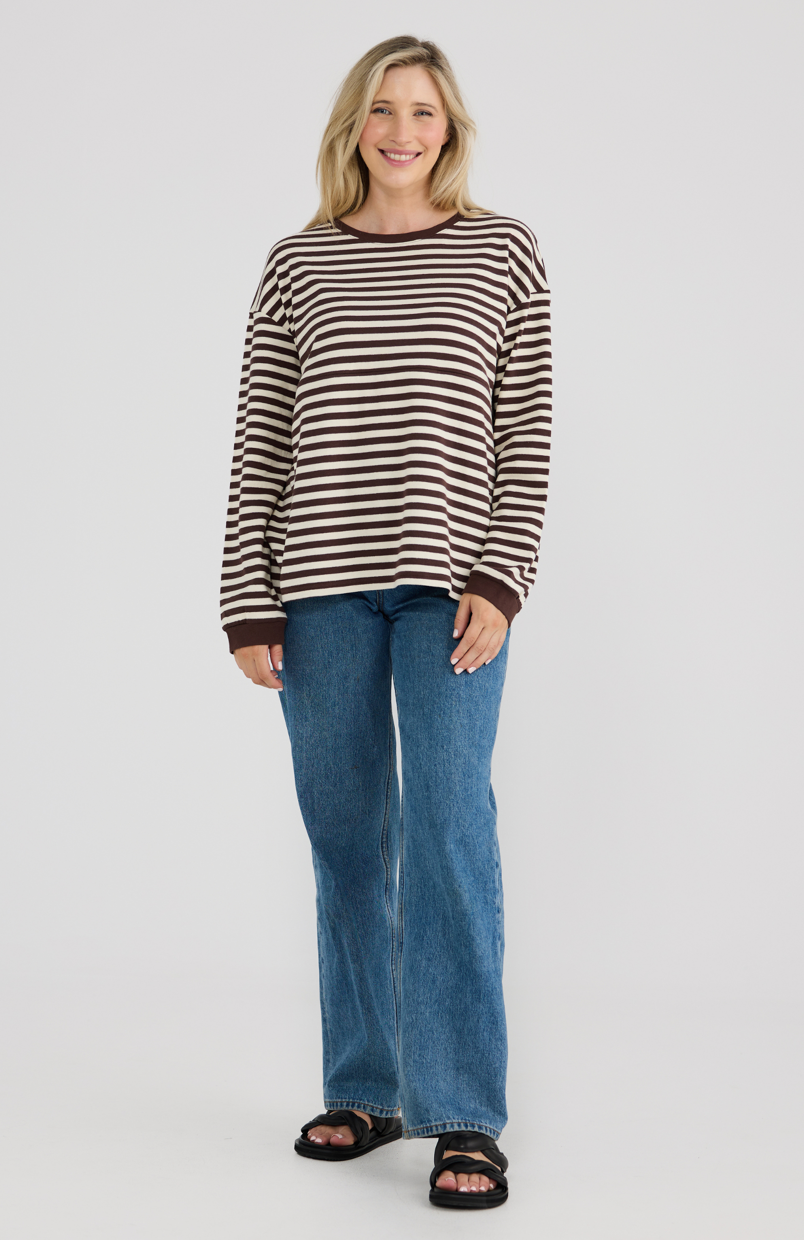 Woman wearing a striped long sleeve top and jeans on a white background