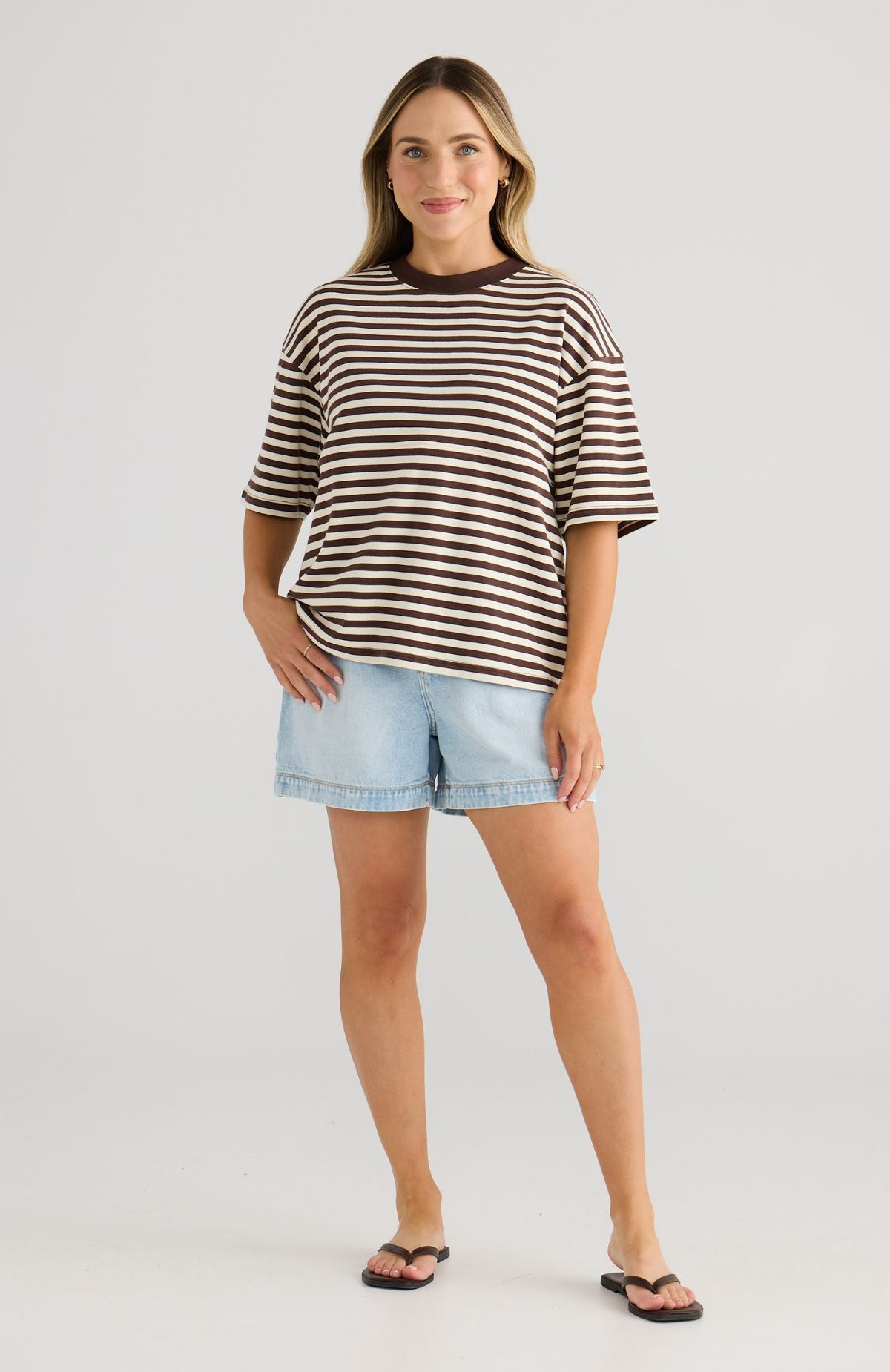 Woman wearing a striped tee and denim shorts on a white background
